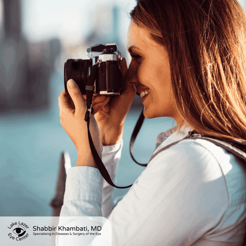 smiling woman holding a camera up to her eye